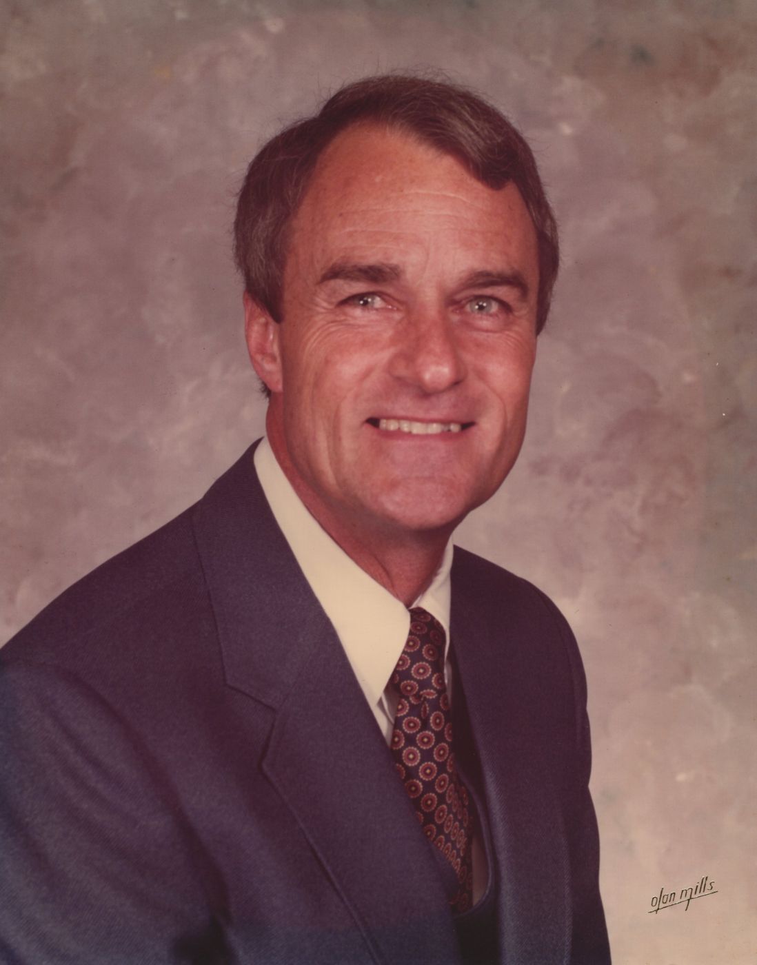 Portrait of Bobby Ray Ward in a navy suit and patterned tie, smiling